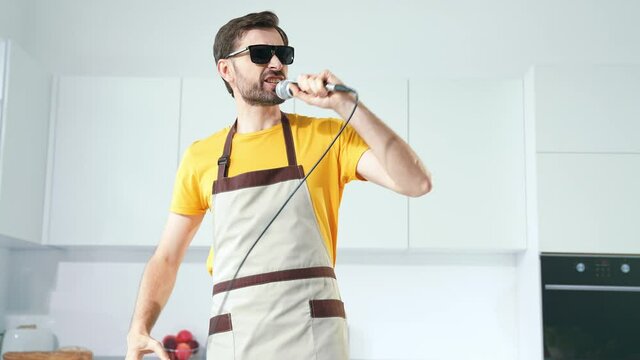 Cheerful guy prepare meal morning imagine stage sing single in kitchen 