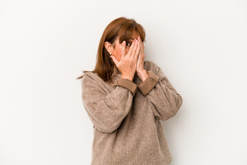 Middle age caucasian woman isolated on white background blink through fingers frightened and nervous.
