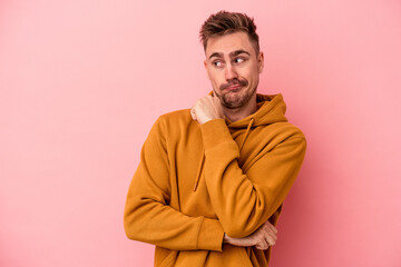 Fototapeta premium Young caucasian man isolated on pink background confused, feels doubtful and unsure.
