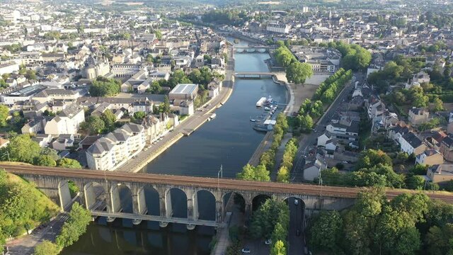 General aerial view of Laval town overlooking arched railway bridge across Mayenne River on summer day, France. High quality 4k footage