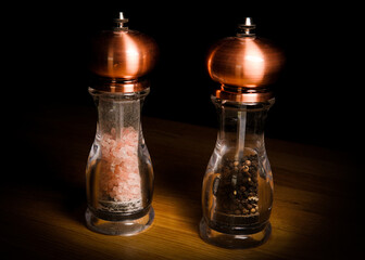 Set of copper salt and pepper grinders isolated on a wooden table