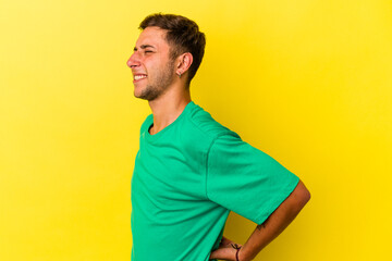 Young caucasian man with tattoos isolated on yellow background  suffering a back pain.