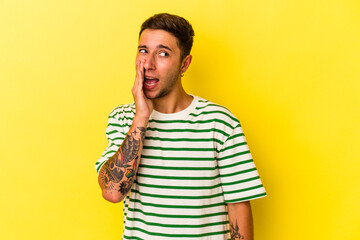 Young caucasian man with tattoos isolated on yellow background  shouting excited to front.