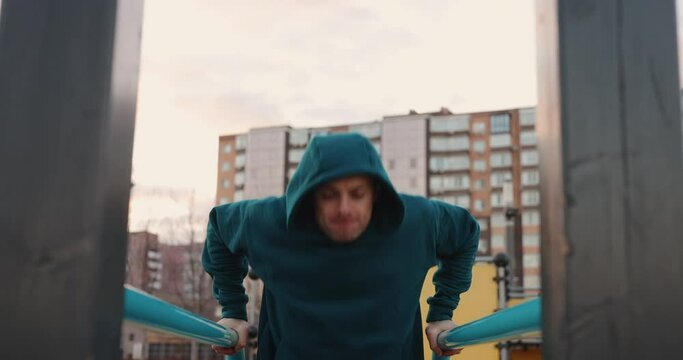 Athletic man doing many pushups on the parallel bars