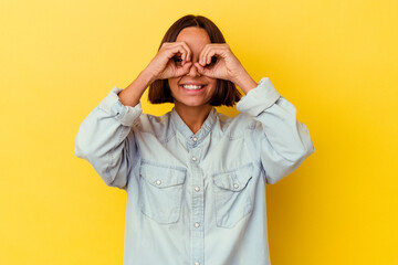 Young mixed race woman isolated on yellow background showing okay sign over eyes