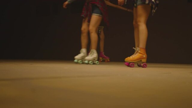 4K Female legs in roller blades, skating fast at the roller park on floor . Close-up legs of young women is professionally skating . Different kind of and colorful vintage  roller blades . Slow Motion