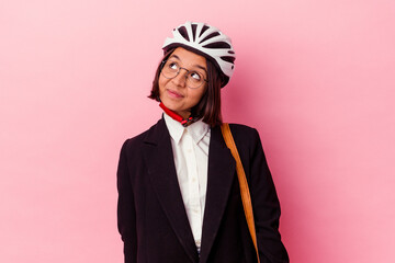 Young business mixed race woman wearing a bike helmet isolated on pink background dreaming of achieving goals and purposes