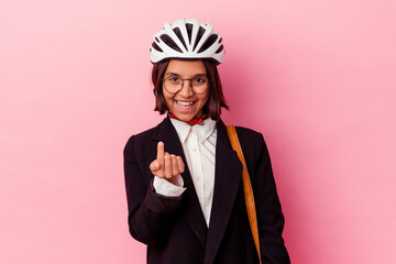 Young business mixed race woman wearing a bike helmet isolated on pink background pointing with finger at you as if inviting come closer.