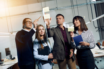 Obraz premium Serious office workers work with the plans on the glass board.