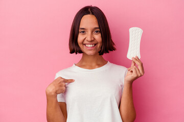 Young mixed race woman holding a compress isolated on pink background person pointing by hand to a...