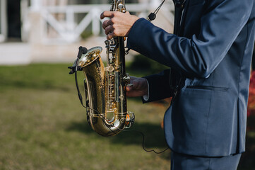 A man in a suit, saxophonist, musician plays the modern saxophone with a microphone. Hands on a...