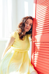 portrait of a beautiful brunette woman in a yellow dress at home