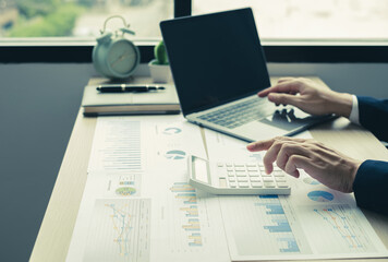 Fototapeta premium The hand of businessman sit at their desks and calculate financial graphs showing results about their investments, plan a successful business growth process