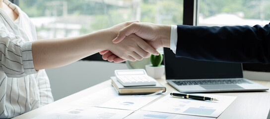 Two business leaders talk about charts, financial graphs showing results are analyzing and calculating planning strategies, business success building processes, and shake hands