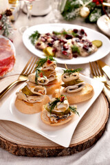 Herring and pickle rolls and other appetizers on Christmas table