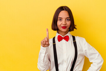 Young mixed race waitress woman isolated on yellow background showing number one with finger.