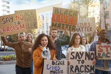 Protesters demonstrating different anti racism slogans outdoors. People holding signs with phrases