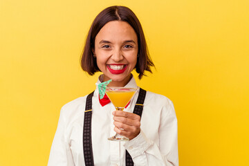 Young pretty bartender woman holding a cocktail on a yellow background