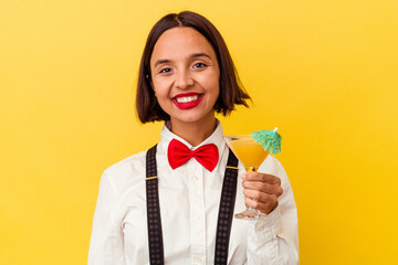 Young pretty bartender woman holding a cocktail on a yellow background