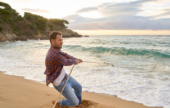 Man pulling rope from sea at beach