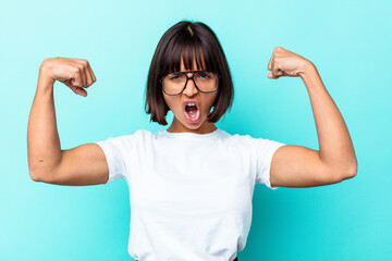 Young mixed race woman isolated on blue background showing strength gesture with arms, symbol of feminine power