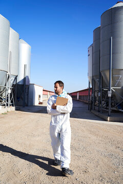 Worker in protective suit at factory on sunny day