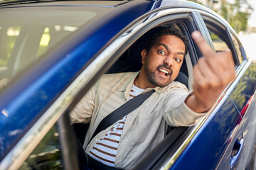 transport, emotions and people concept - angry indian man or driver driving car and showing middle...