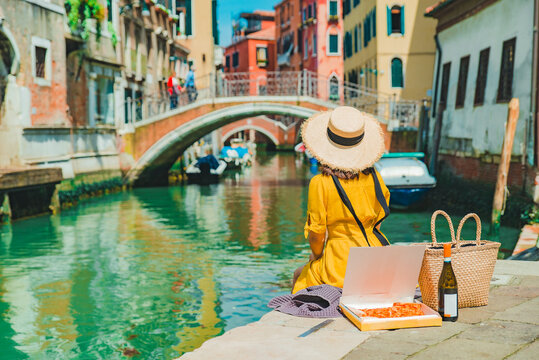 woman sitting on pier looking at gandolas at venice canal