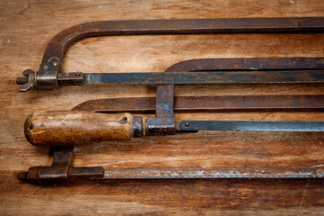 Old vintage metal hacksaws for metal shot on a wooden background.