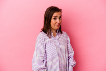 Obraz premium Middle age caucasian woman isolated on pink background shrugs shoulders and open eyes confused.