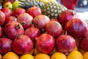 Pomegranate and tropical fruits, bananas, pineapples, lemons, citrus fruits on display at market. Fresh organic  fruits for smoothies, fruit salad, juice