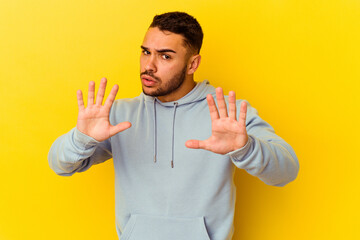 Young caucasian man isolated on yellow background rejecting someone showing a gesture of disgust.