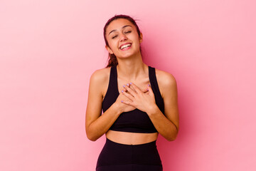 Obraz na płótnie Canvas Young sport Indian woman isolated on pink background laughing keeping hands on heart, concept of happiness.