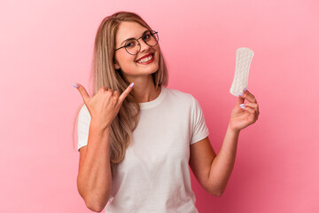 Young russian woman holding a compress isolated on pink background showing a mobile phone call gesture with fingers.