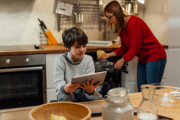 mother and her son looking recipes on digital tablet in kitchen