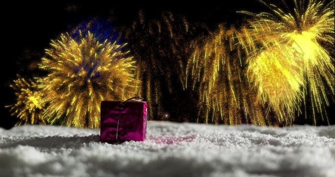 Animation of christmas present in snow and yellow fireworks exploding in night sky
