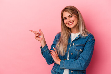 Young russian woman isolated on pink background smiling cheerfully pointing with forefinger away.