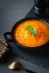 Pumpkin soup and rye bread on gray table