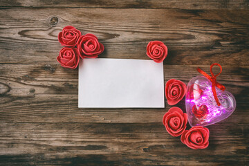transparent heart with light garland, red roses and blank card, Valentine's day background