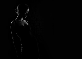 Fototapeta na wymiar Silhouette profile of a young beautiful woman on a dark background. Place for text about beauty and health.