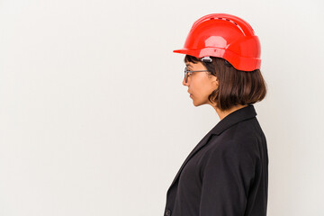 Young architect woman with red helmet isolated on white background gazing left, sideways pose.