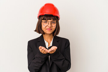 Young architect woman with red helmet isolated on white background holding something with palms, offering to camera.