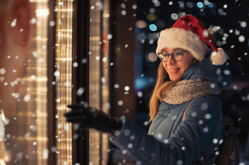 Pretty Woman in Santas hat looking and dreaming in illuminated shop window. Xmas presents holidays, or shopping on New Year or Christmas concept