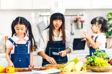 Portrait of enjoy happy love asian family mother and little asian girl daughter child having fun help cooking food healthy eat together with fresh vegetable salad and sandwich ingredient in kitchen