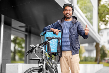 Fototapeta na wymiar food shipping, profession and people concept - happy smiling delivery man with thermal insulated bag and bicycle on city street showing thumbs up