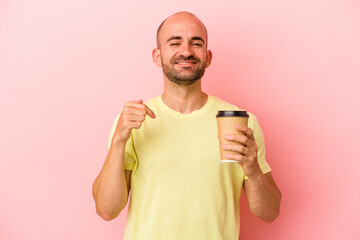Young caucasian bald man holding a take away coffee isolated on pink background  person pointing by hand to a shirt copy space, proud and confident