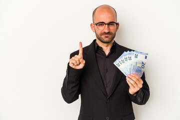 Young business bald man holding bills isolated on white background  showing number one with finger.