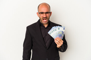 Young business bald man holding bills isolated on white background  screaming very angry and aggressive.