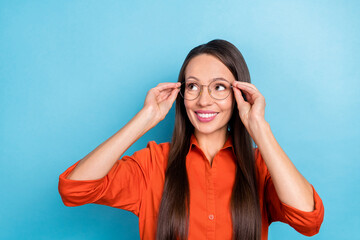 Photo of pretty dreamy mature lady dressed red shirt arms glasses smiling looking empty space isolated blue color background