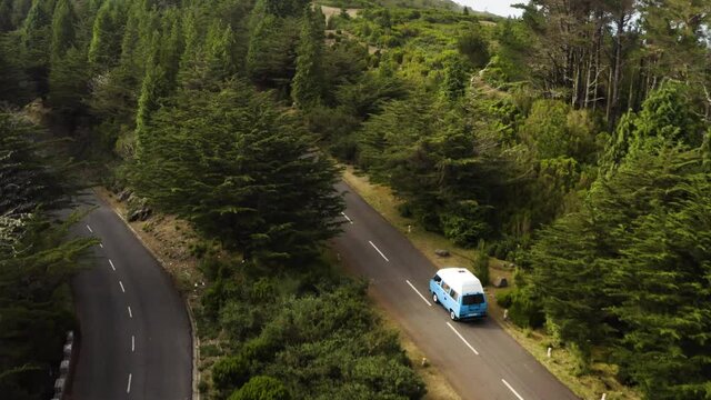 Aerial follows a VW-Camper van that drives on a empty road on Madeira, Portugal